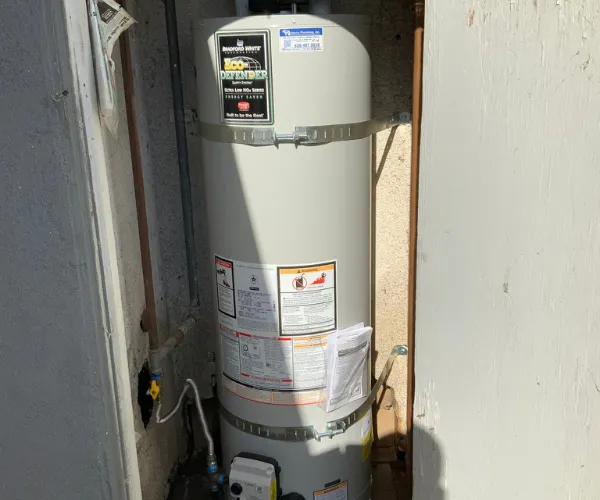 A section of copper plumbing featuring significant limescale buildup and crusting around the threaded connections and valves.