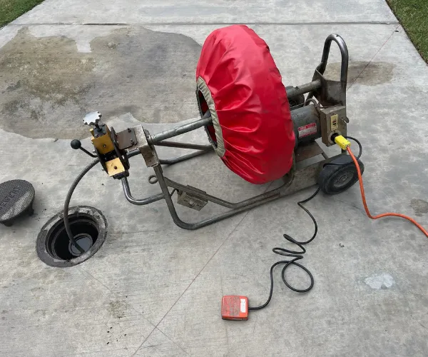 A section of copper plumbing showing heavy limescale buildup and corrosion at a T-junction connector.