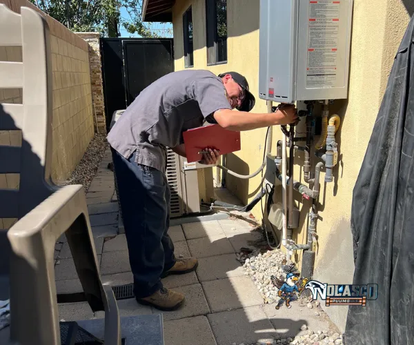 Section of copper plumbing with significant limescale buildup on threaded connections and valves.